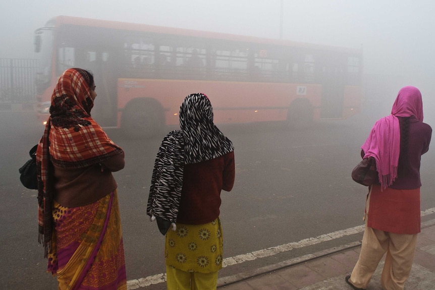 Delhi commuters wait for a bus in smog