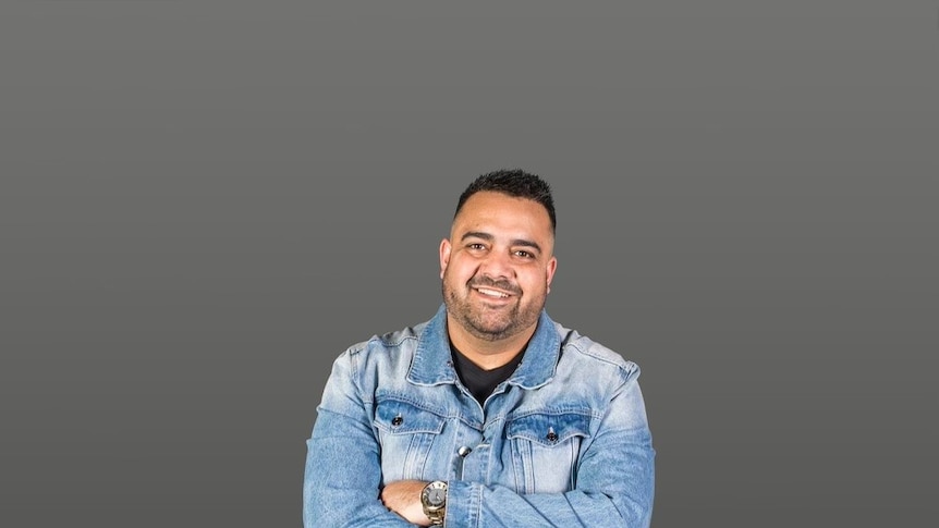 Indigenous comedian Dane Simpson arms folded smiling at the camera