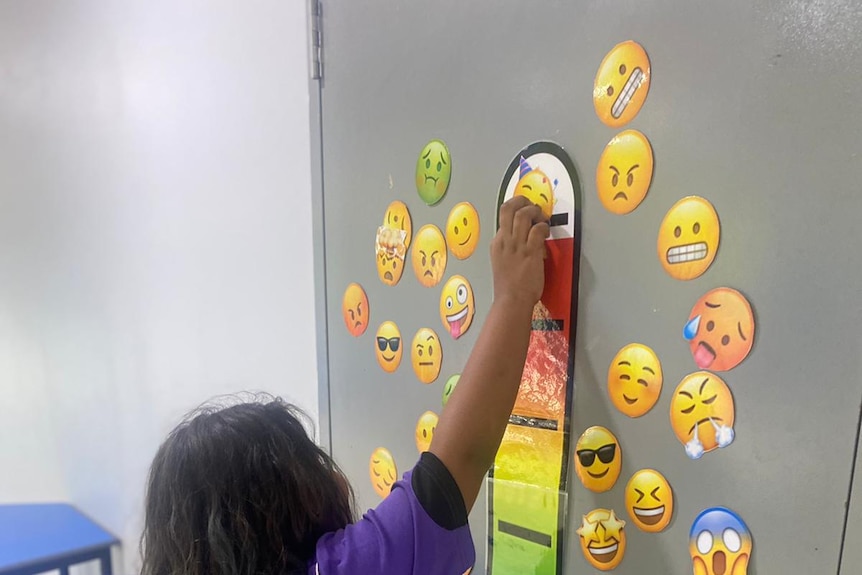 A child placing a emoji pictures on a temperature gage