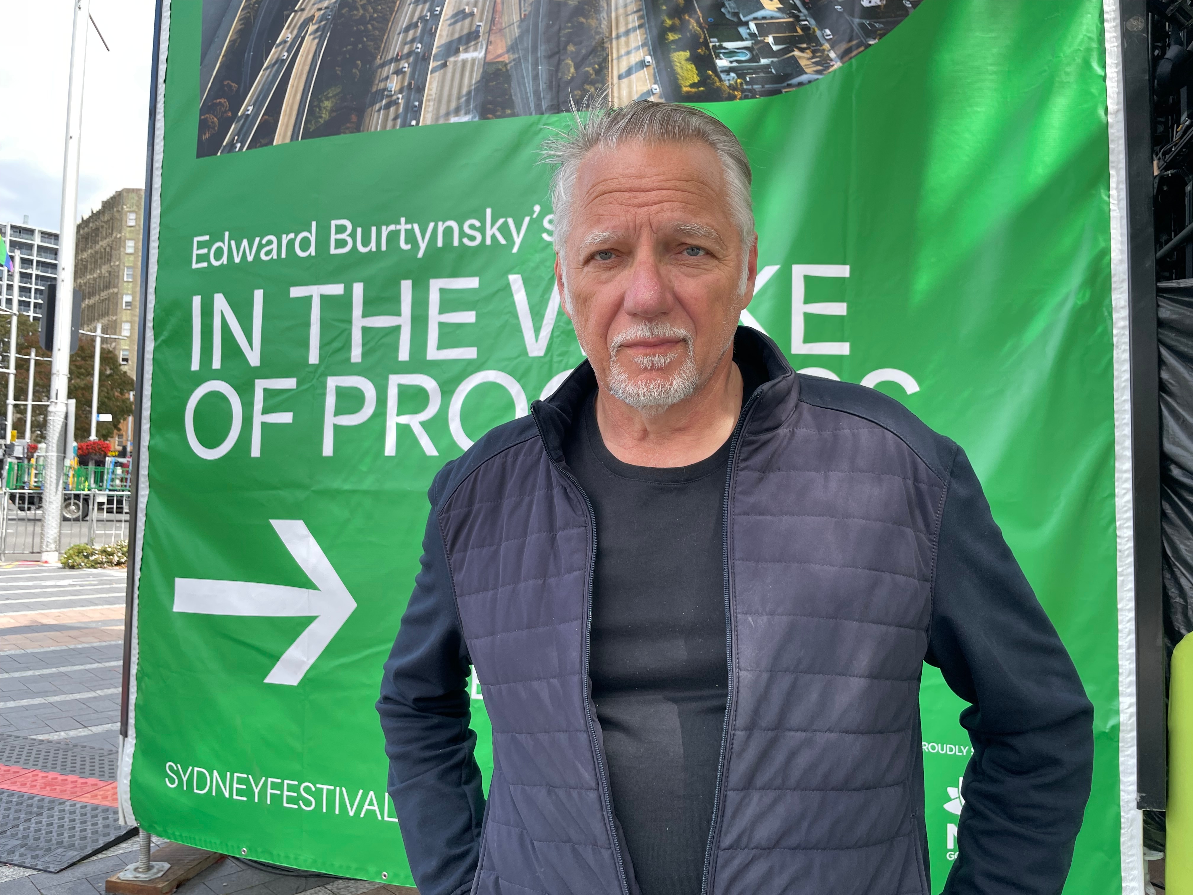 A man standing in front of a green poster