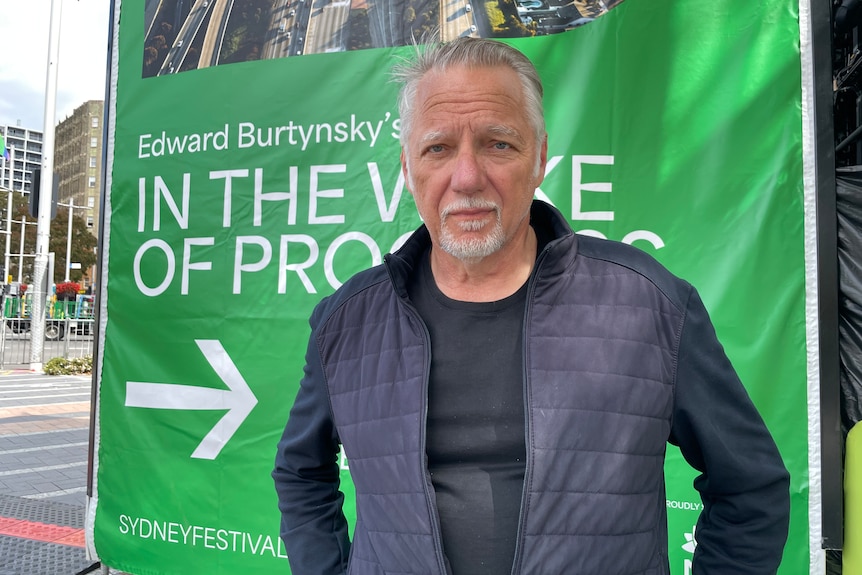 A man standing in front of a green poster