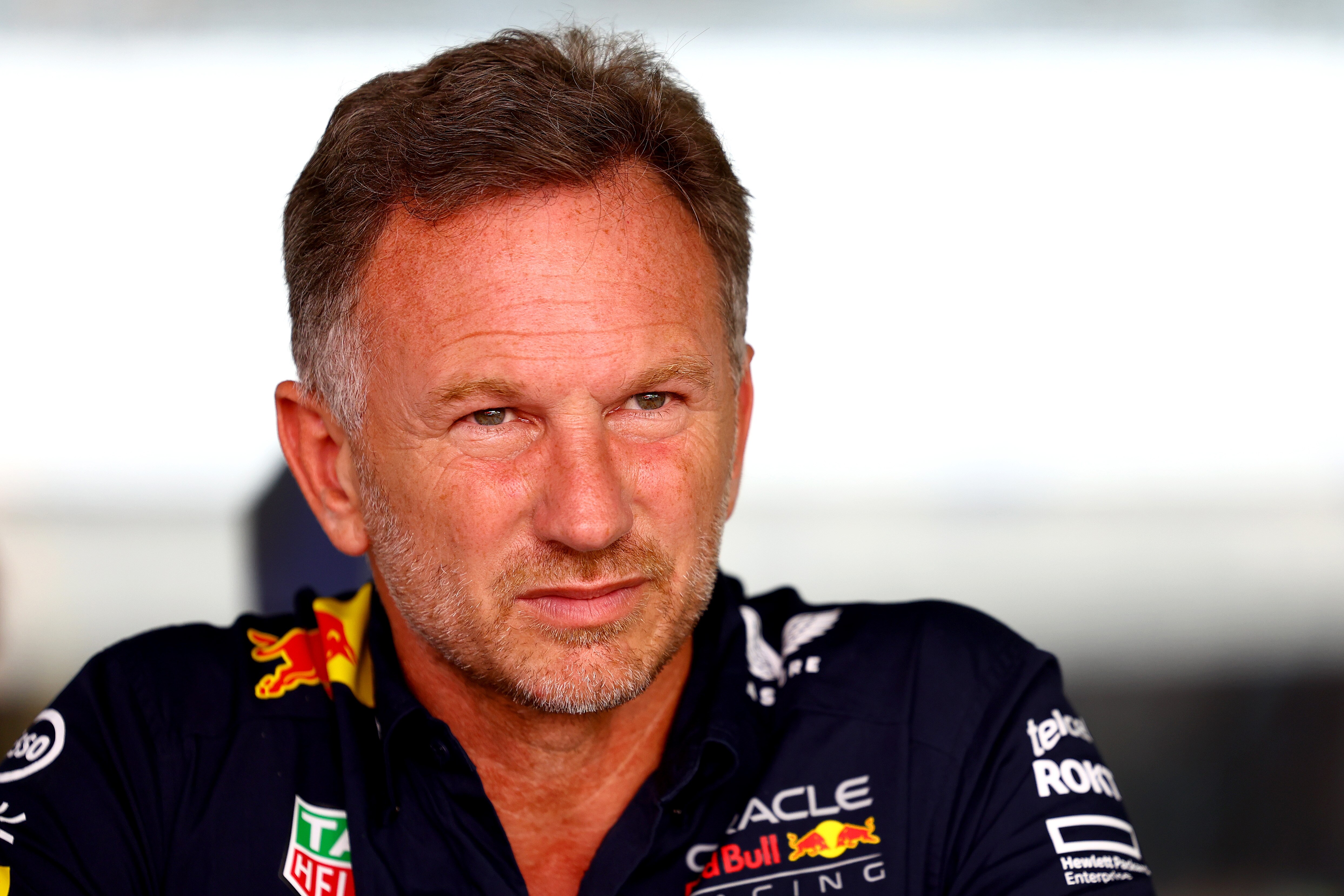 Christian Horner, in a blue polo shirt, looks into the distance during a practice session.
