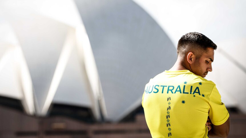 Rugby player Maurice Longbottom models the Australian Olympic team's tshirt next to the Sydney Opera House