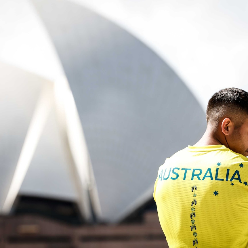 Rugby player Maurice Longbottom models the Australian Olympic team's tshirt next to the Sydney Opera House
