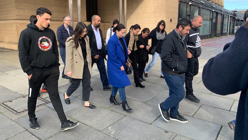 A group of 10 family members walking outside a court building