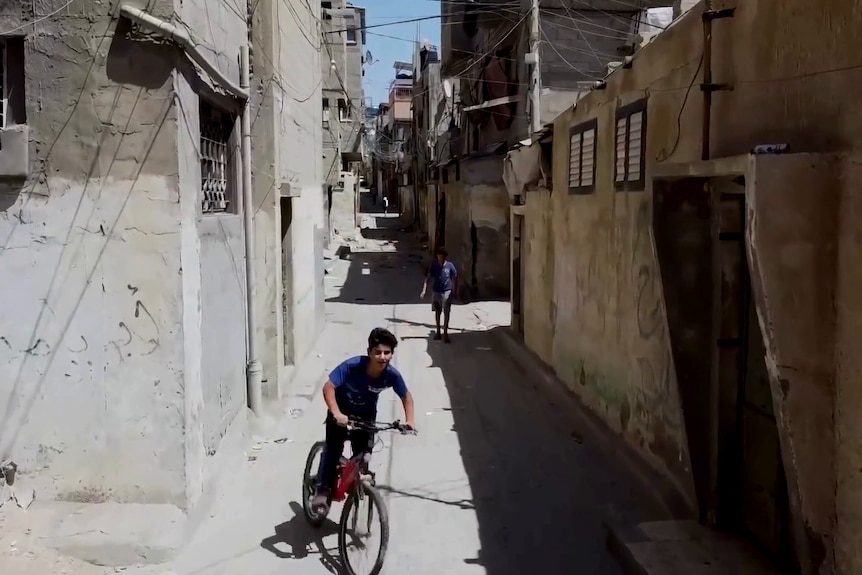 children walk and ride bikes throuh narrow streets 