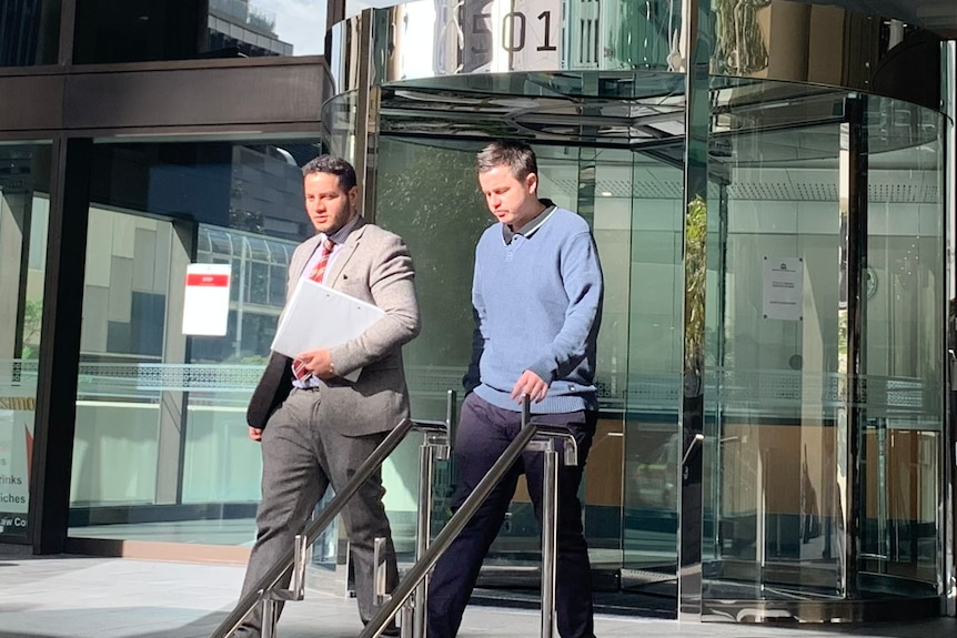 Two men pictured next to a revolving door.