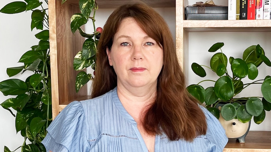 A woman standing in front of a book shelf.