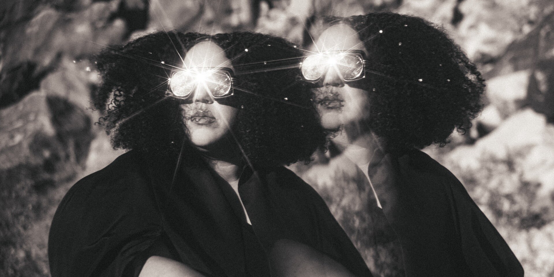 Black and white photo of Brittany Howard wearing kaleidoscopic goggles with a mirror image