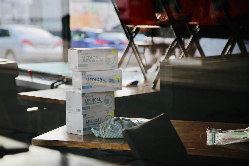 Four boxes of surgical masks stacked on a desk.