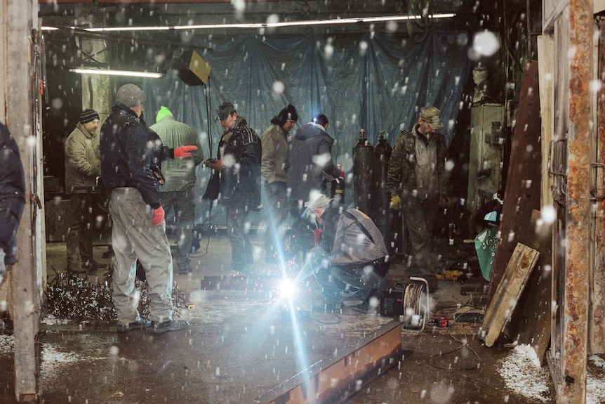 sparks fly in front of a group of men working in a metal workshop