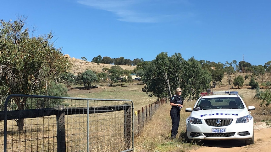 A police officer stands outside a property where a family was subjected to a home invasion.