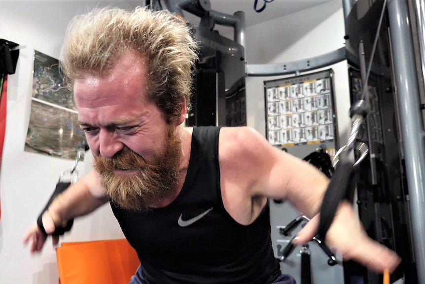 Man in black singlet does bench presses.