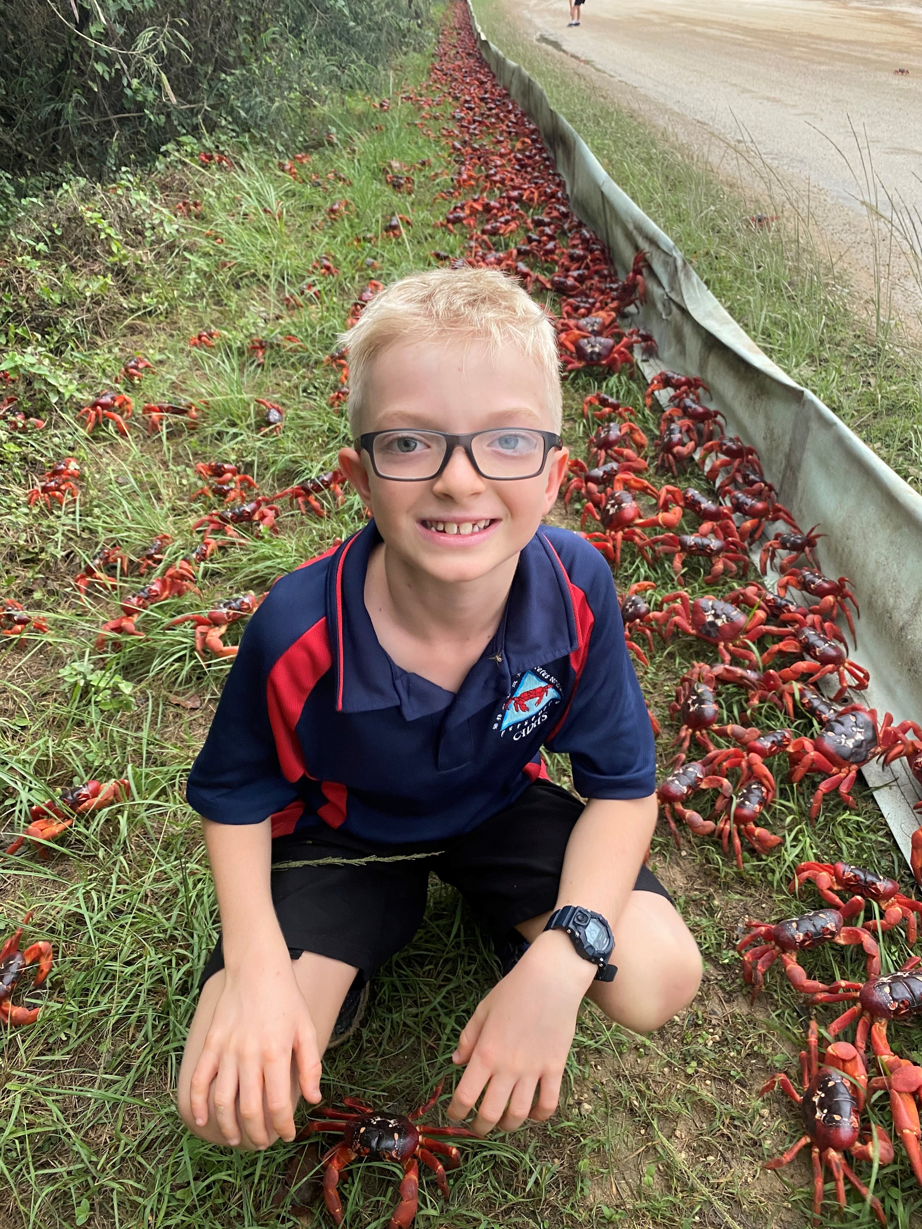 Christmas Island resident Jacob Tiernan-Luetich crouching next to the crabs.