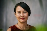 A close-up of a middle-aged Asian woman with short black hair looking at the camera