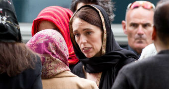 Jacinda Ardern, wearing a headscarf, walks to mourners