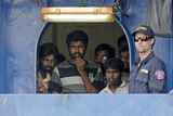 An Australian customs official keeps watch as Sri Lankan refugees look out from the Oceanic Viking