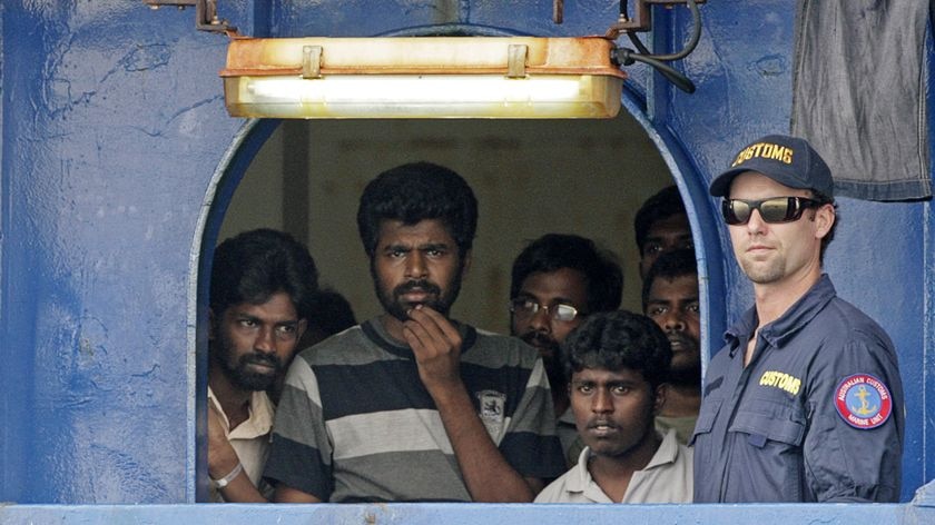 An Australian customs official keeps watch as Sri Lankan refugees look out from the Oceanic Viking