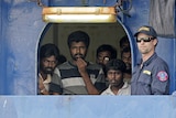 An Australian customs official keeps watch as Sri Lankan refugees look out from the Oceanic Viking