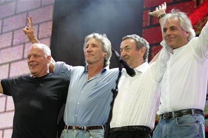 Four members of Pink Floyd arm-in-arm on stage.