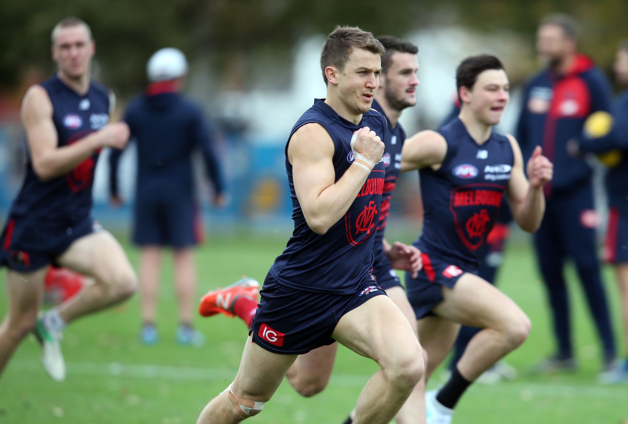 Aussie Rules players run across the field during a training exercise.