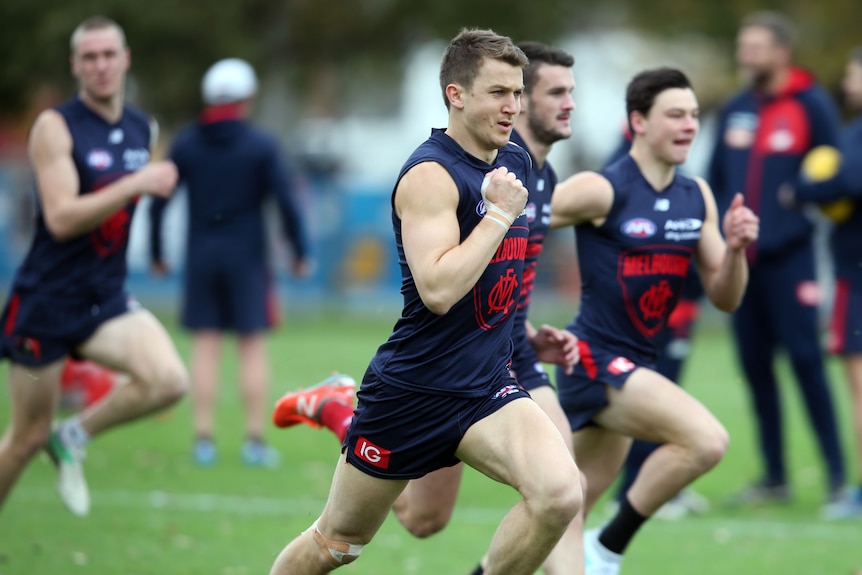 Aussie Rules players run across the field during a training exercise.