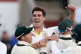 Pat Cummins celebrates as teammates rush to him after taking a wicket
