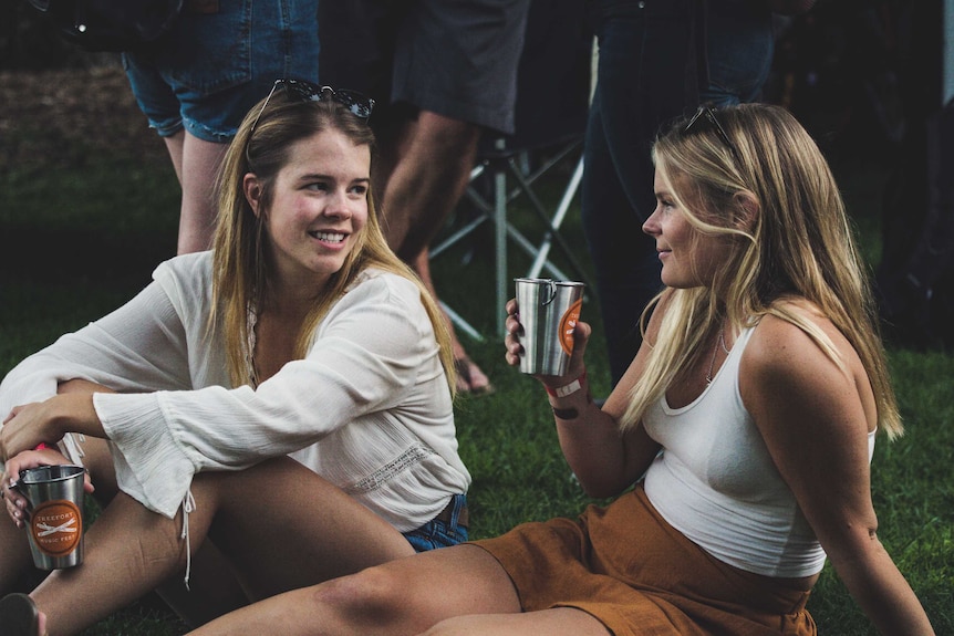 Two women sit on the lawn talking to each other to depict a story about women experiencing baby panic.