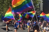 Marchers wave rainbow flags.