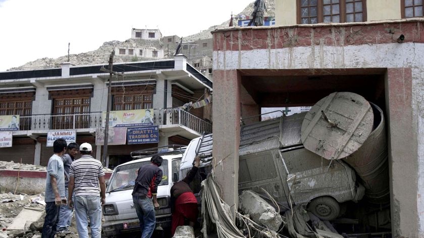 People try to remove cars that damaged a prayer wheel (Mane Tungchur) after flash floods in Leh
