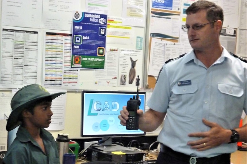 A police officer showing a two-way radio to a young student.