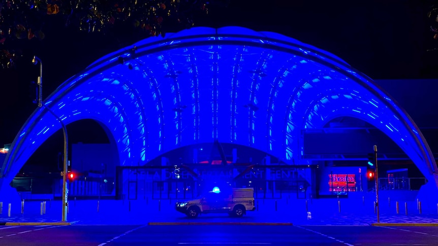 The Adelaide Entertainment Centre dome lit in blue, with a police vehicle blue light in the foreground.