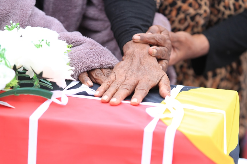 Hands on a box wrapped in the Aboriginal flag
