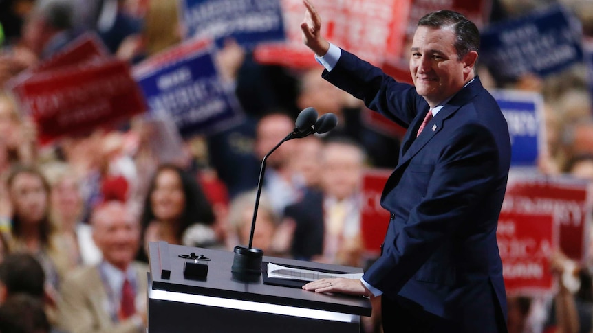 Ted Cruz waves at the crowd while standing at a podium