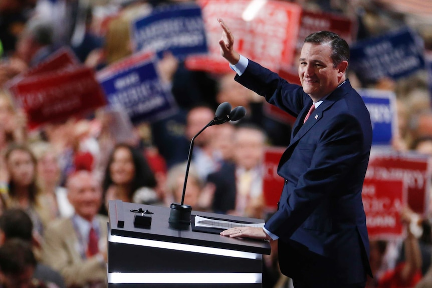 Ted Cruz waves at the crowd while standing at a podium