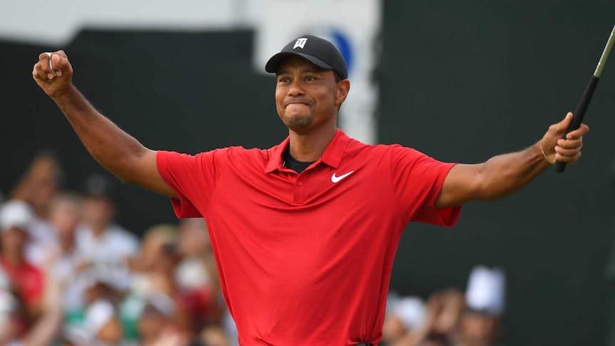 A man wearing red raises his arms with a smile on his face