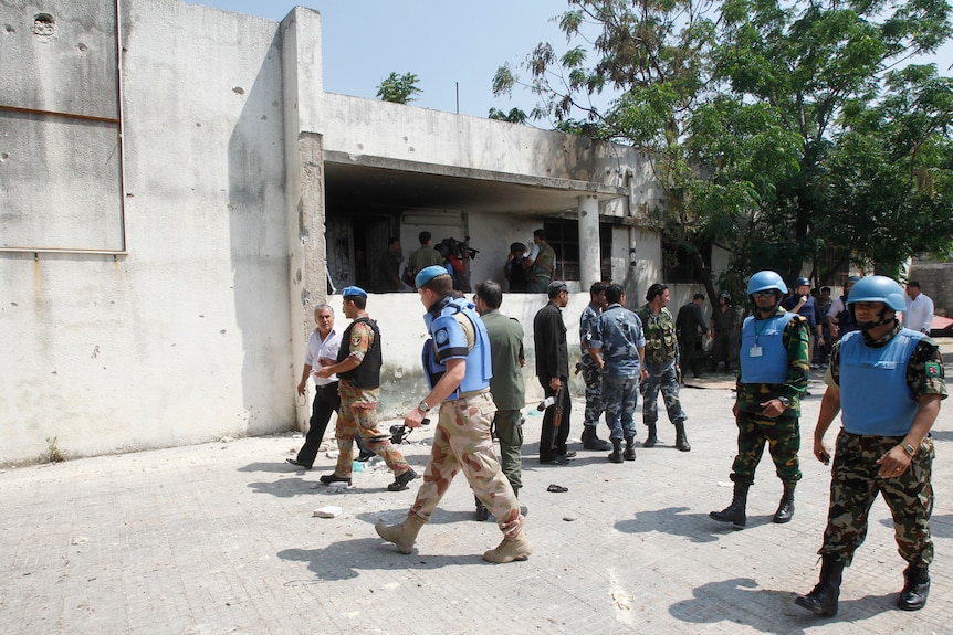 Members of the United Nations observer mission in Syria are seen at a burnt building in Al-Heffah, in Latakia province.