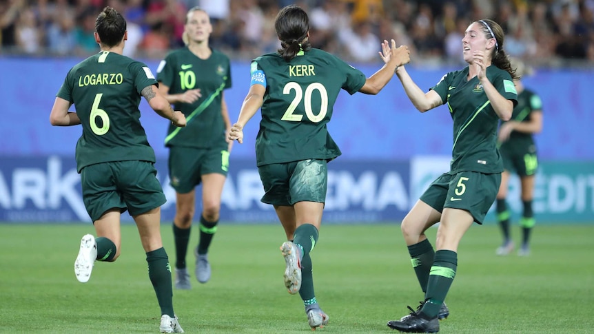 Sam Kerr celebrates a goal by giving a high five to a teammate as she runs away from the camera
