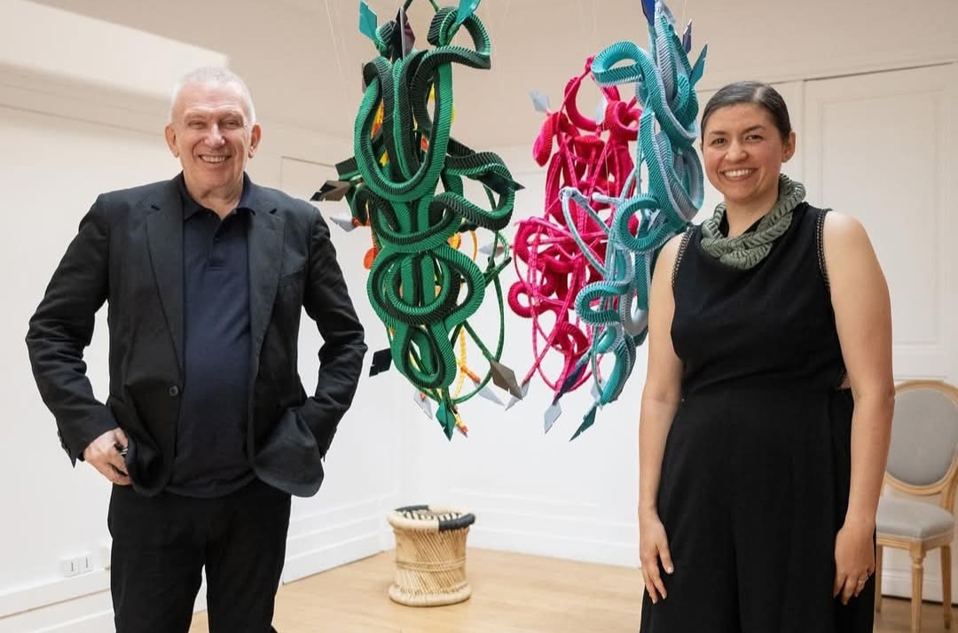 Homem e mulher ao lado de esculturas penduradas