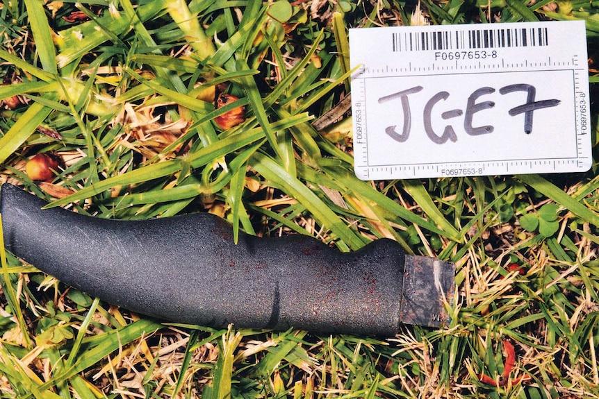 The bloodied handle of a knife used to stab Alex Boreski lies in grass with its blade missing and a white card alongside it.