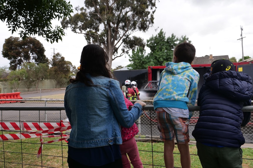 A group of children watch the CFA put out a fire