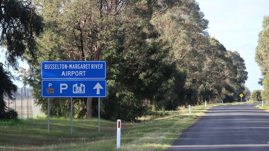 A road sign pointing to the Busselton-Margaret River Airport on the side of the road.