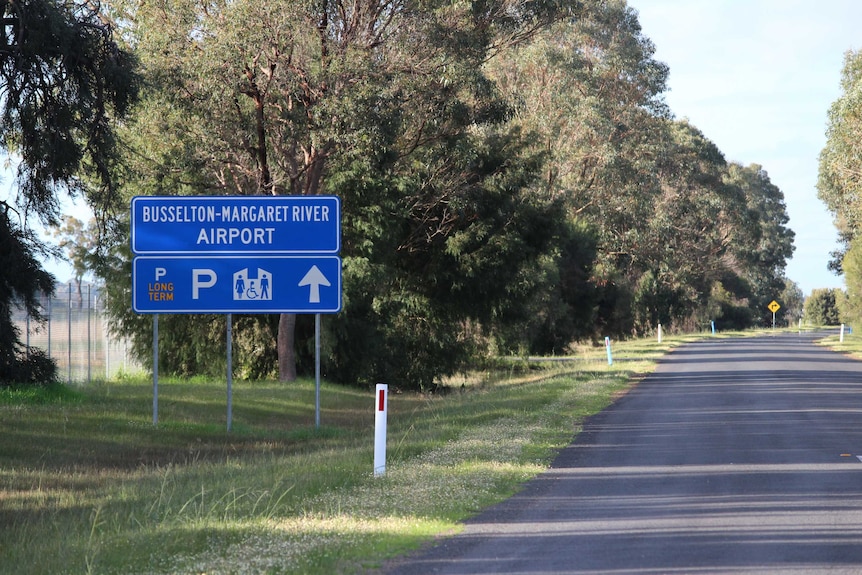 A road sign pointing to the Busselton-Margaret River Airport on the side of the road.