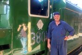 Train driver standing in front of train with number 3801 on side of it.
