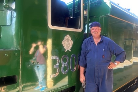 Train driver standing in front of train with number 3801 on side of it.