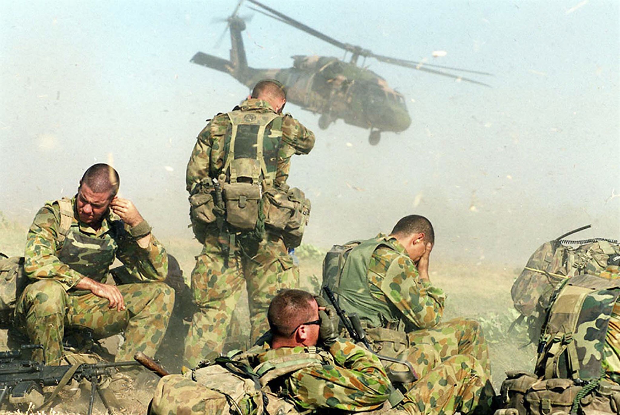 Australian soldiers shield their eyes from the wind as helicopters depart after deploying troops in Balibo.