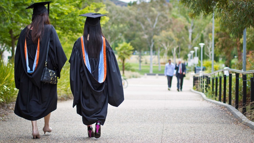 Two women wearing University graduation gowns and mortar boards.