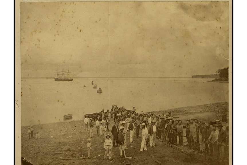 An old photo of a group of people standing on the beach at Port Darwin