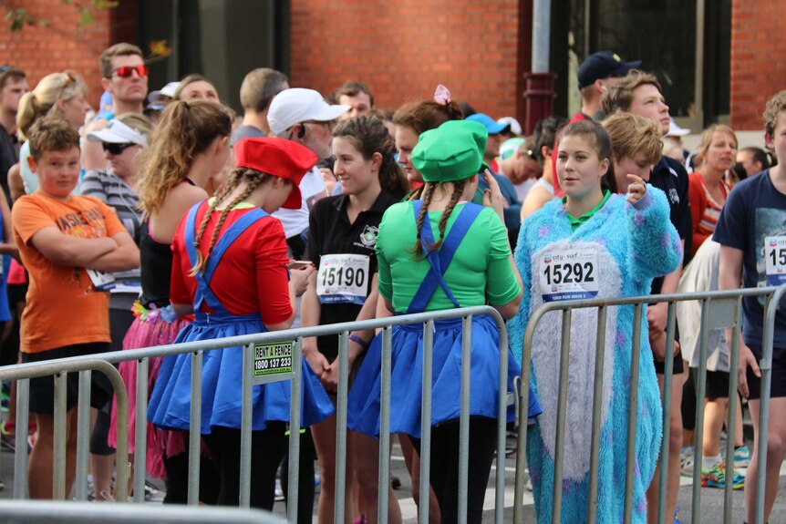 People queue at the City to Surf, including some wearing Super Mario costumes.