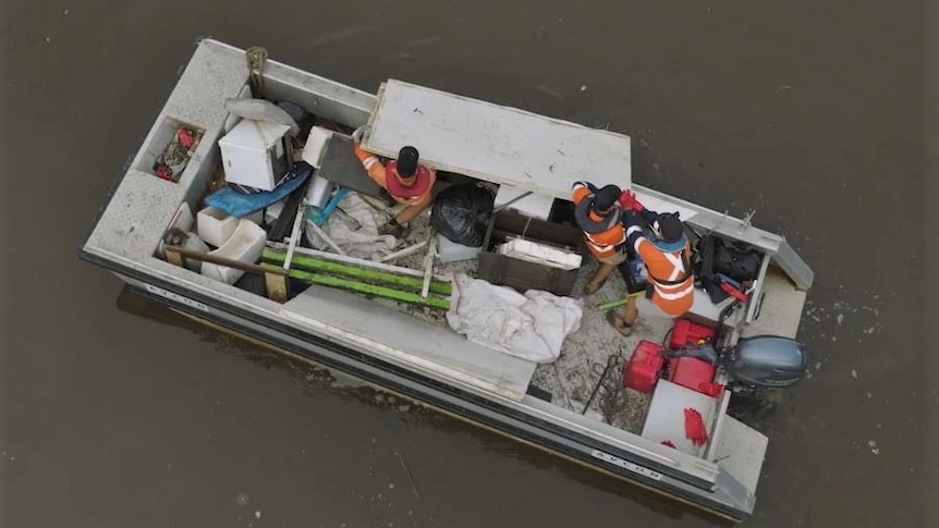 drone birds eye shot of crews in high vis removing something from the river